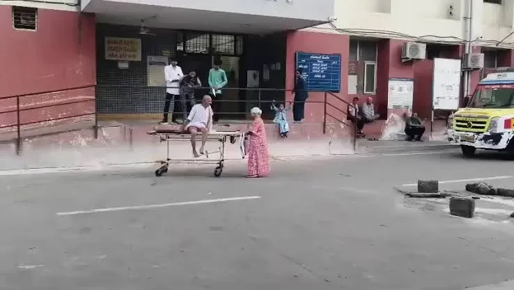 An elderly woman pulls a stretcher carrying her sick husband at PDU Civil Hospital in Rajkot